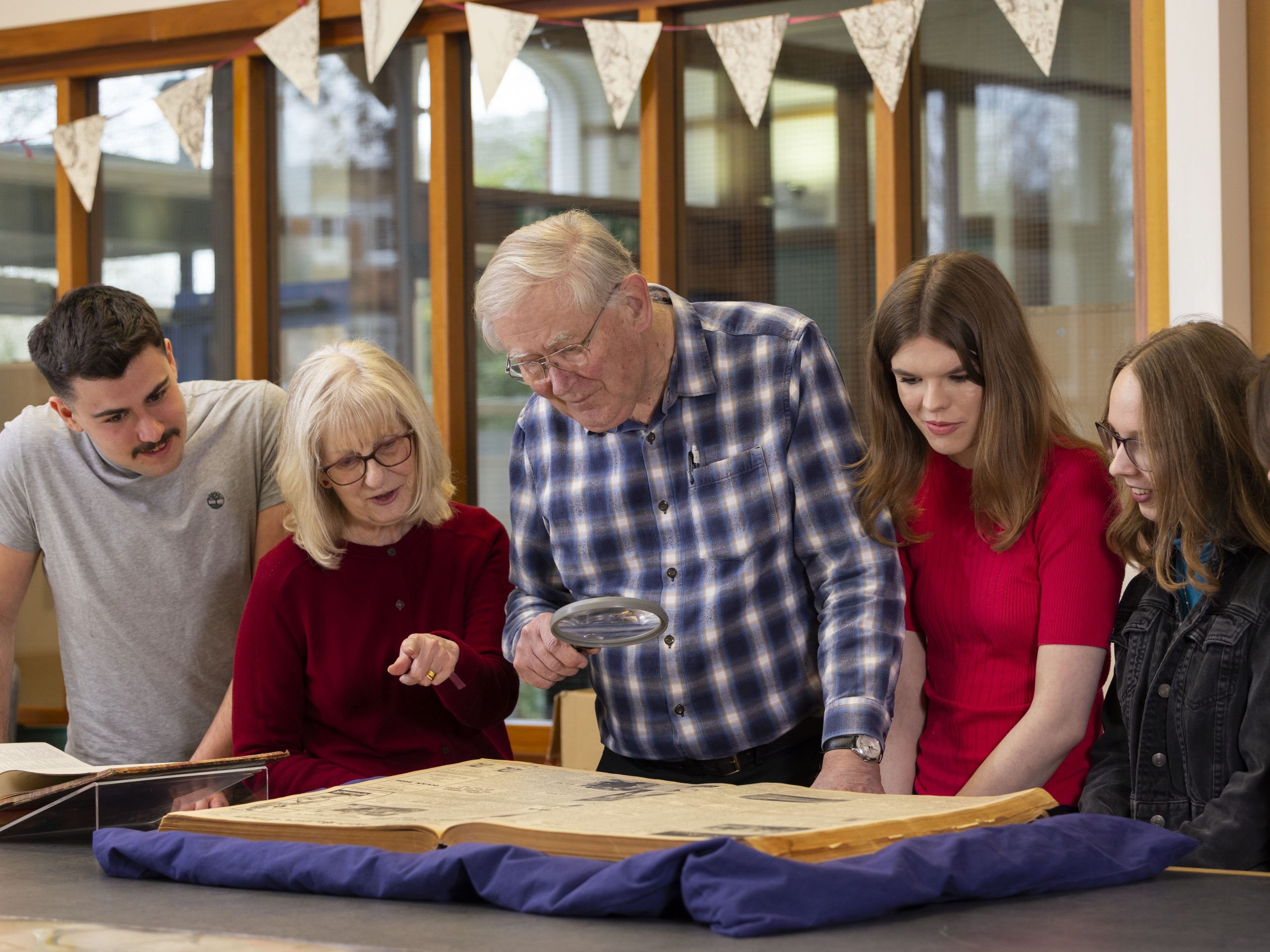 Photo taken from the records office while a workshop was taking place. A group of 5 people are gathered in front of a publication with a microscope.